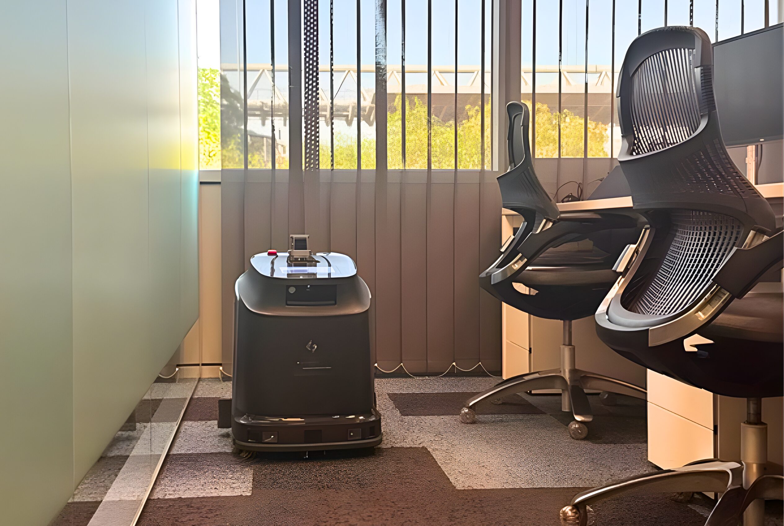 The Gausium Phantas robotic floor cleaner in an office behind some desks and desk chairs