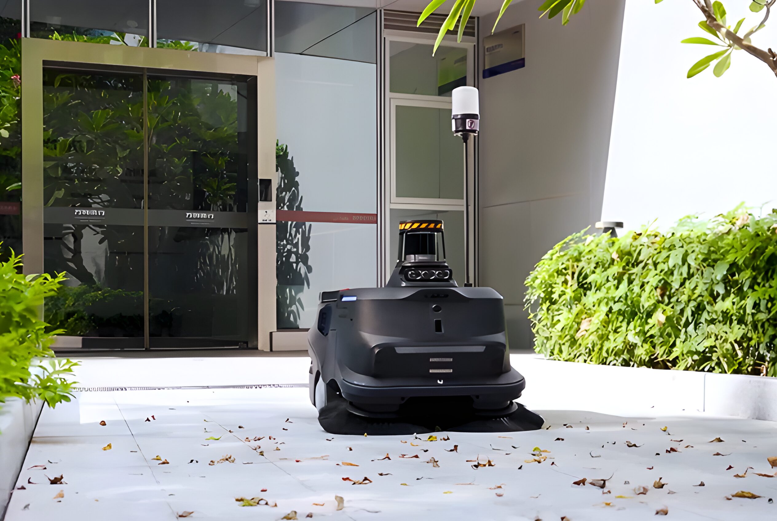 PUDU MT1 Max, an Indoor/outdoor robotic floor cleaning robot outside of an office building clearing a path of leaves